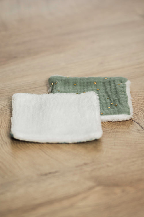 Lot de deux carrés démaquillants réutilisables, un en gaze de coton vert à motifs dorés et un face douillette blanche.