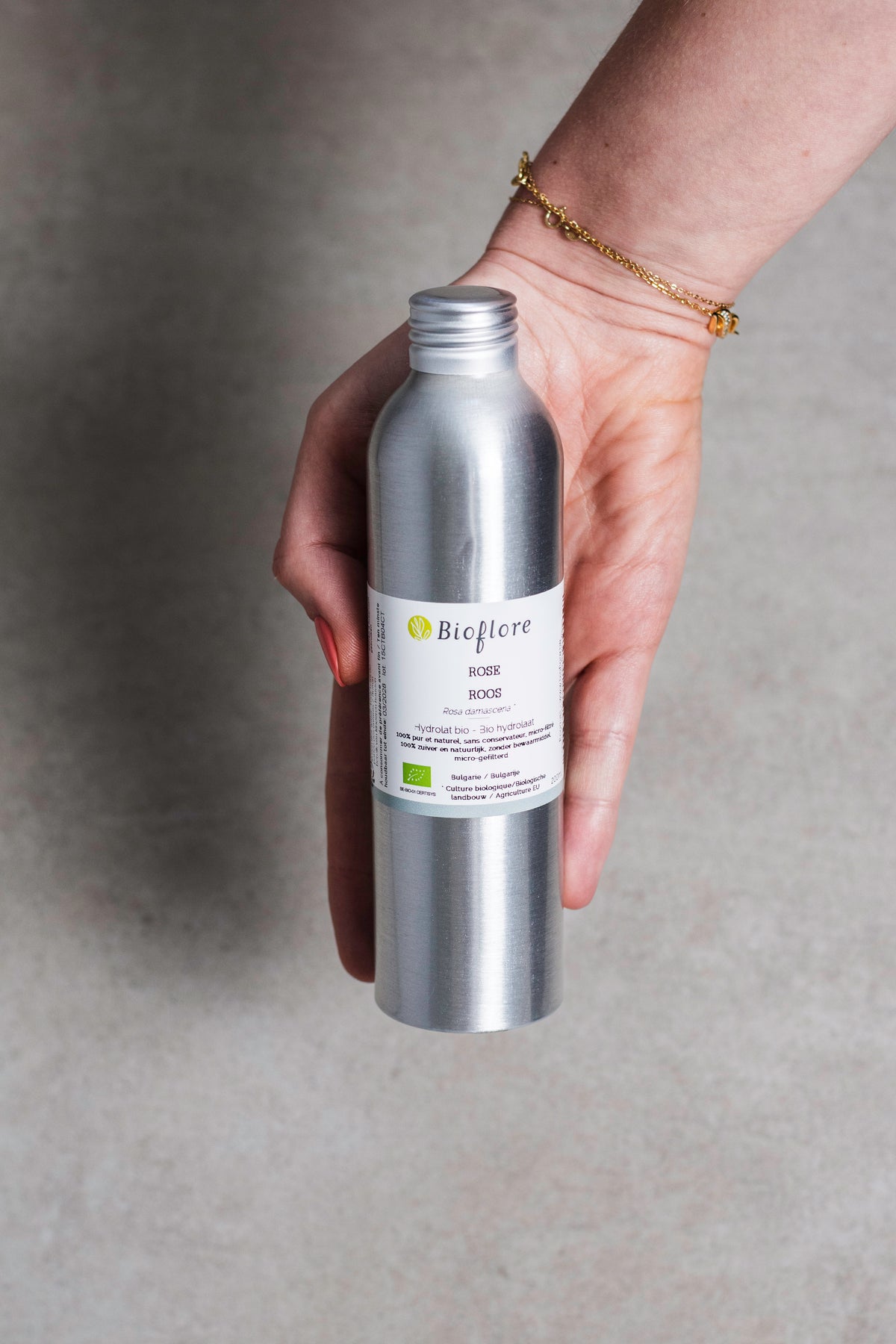 Flacon en aluminium d'hydrolat bio de rose de la marque Bioflore tenu dans la main.