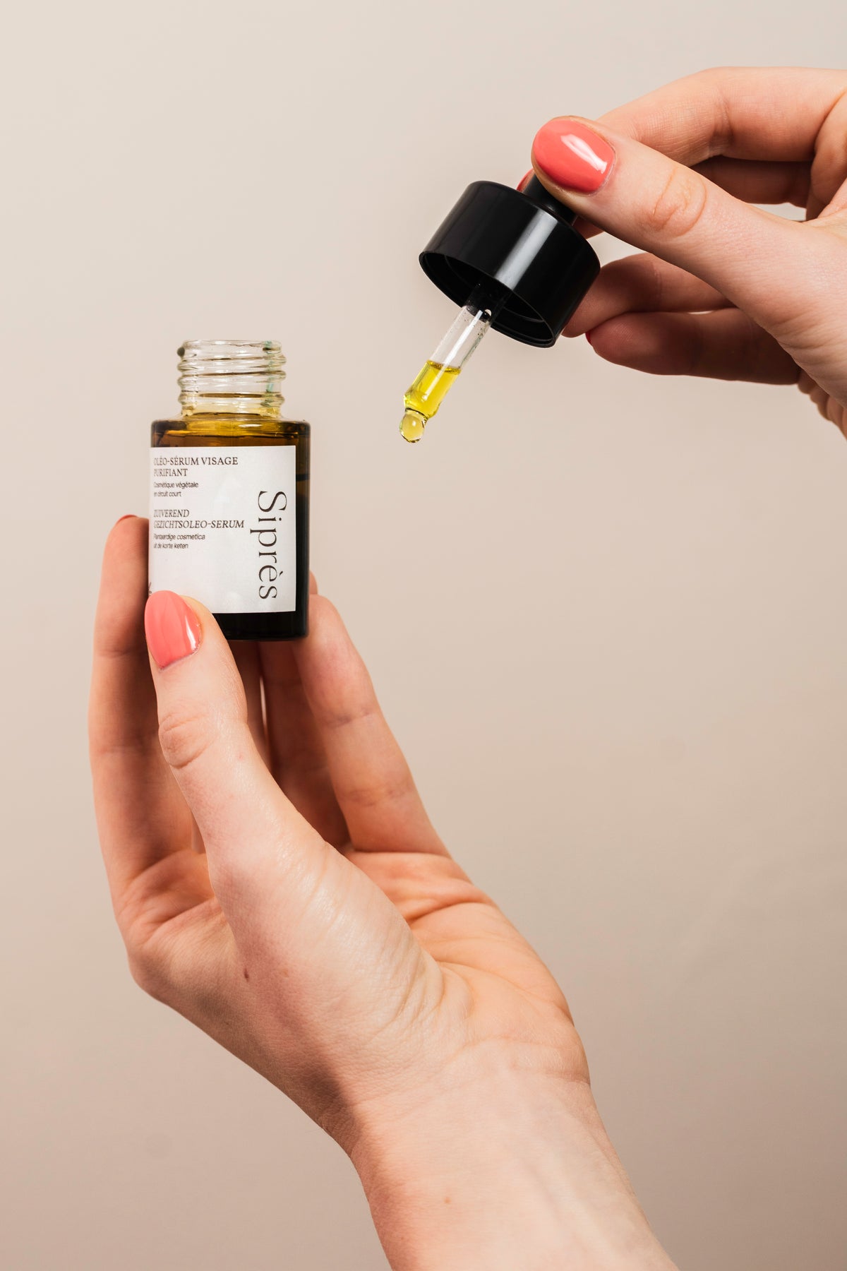 Flacon et pipette d'oléo-sérum visage purifiant Siprès avec goutte de soin appliquée par la main