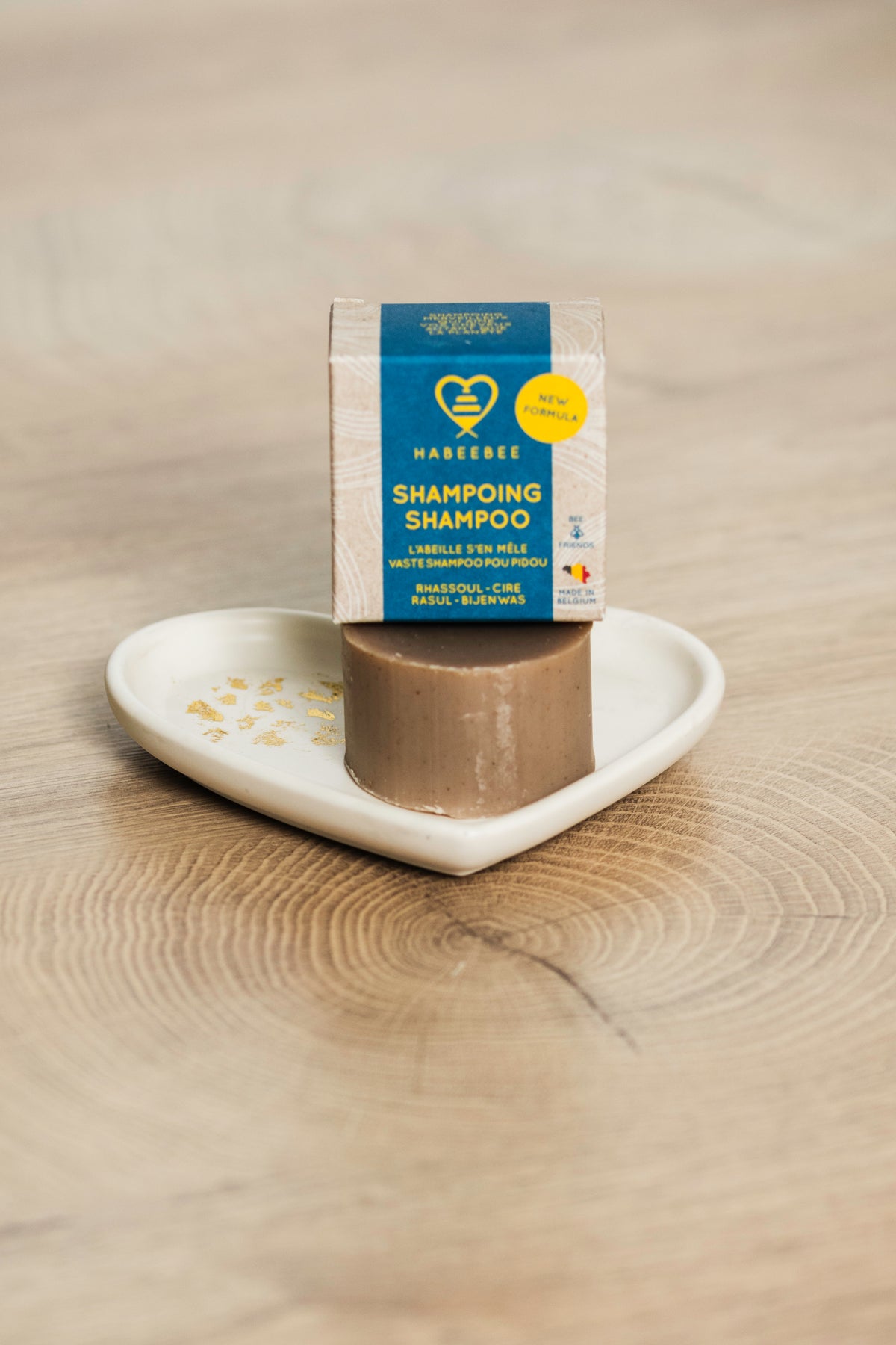 Shampoing solide naturel Habeebee au rhassoul et cire d'abeille, posé avec son emballage sur un porte-savon en forme de cœur.